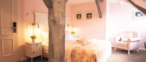 Un dormitorio con cama, mesita de noche, silla y vigas de madera.