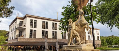 A building with a balcony and a statue of a horse and rider in front.