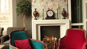 Una habitación con chimenea, dos sillones, una mesa y la cabeza de un ciervo montada en la pared.