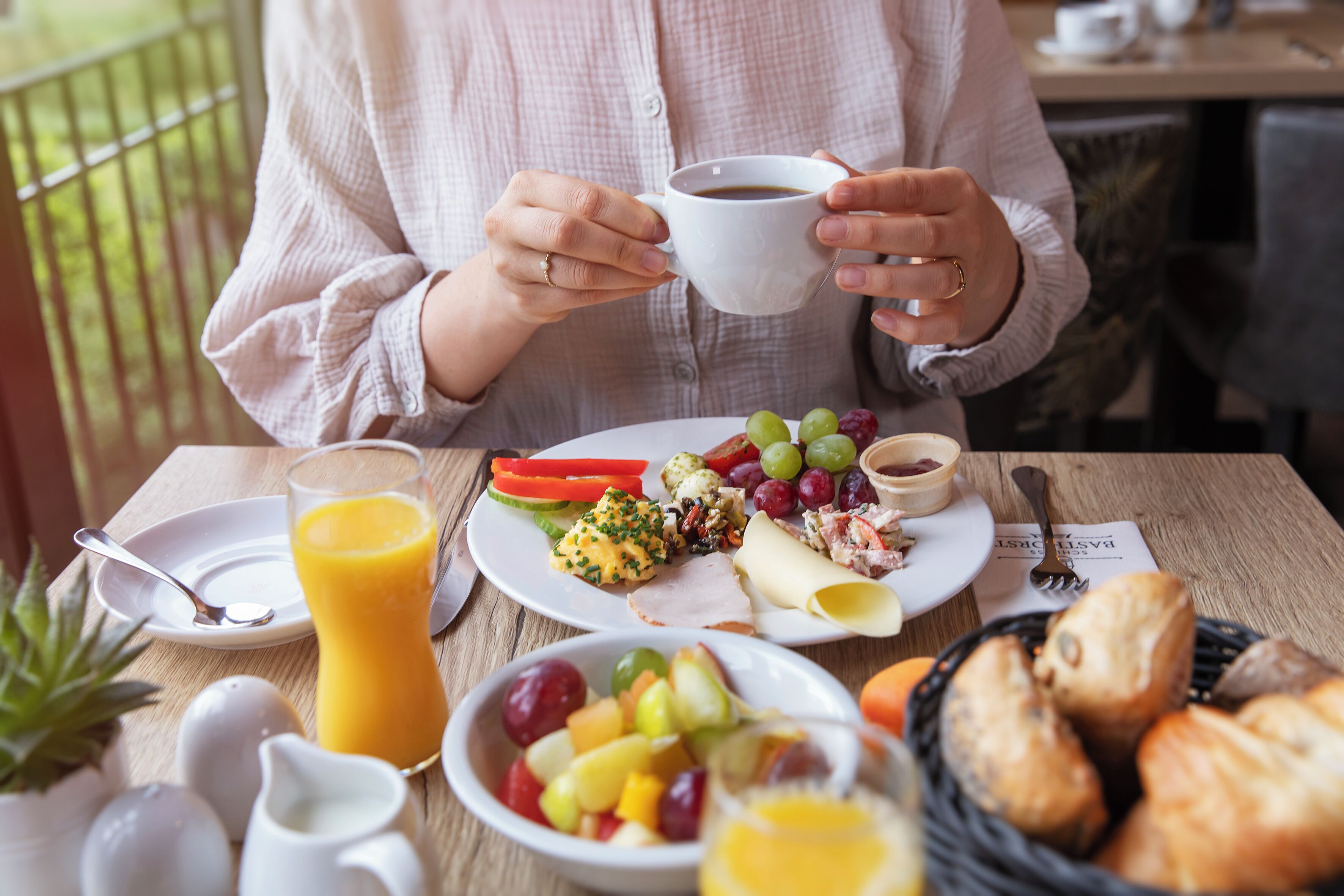 Un desayuno con un plato de comida, un vaso de jugo de naranja y una taza de café.