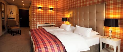 Una habitación de hotel con una cama grande, dos mesitas de noche con lámparas, un cabecero, un banco y un armario.