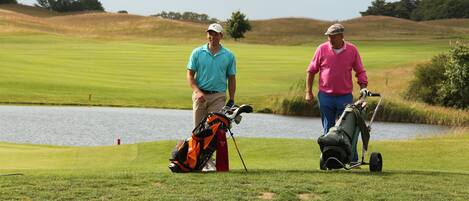 Two people on a golf course with a lake in the background.
