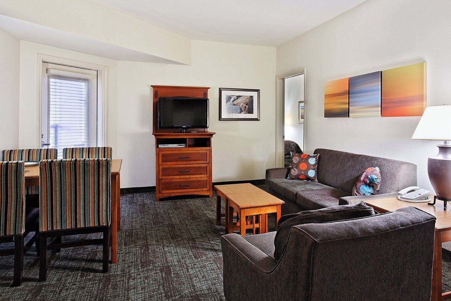 Ein Hotelzimmer mit Sofa, Sessel, Fernseher und kleinem Tisch.