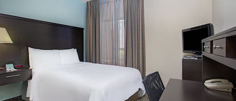 Una habitación de hotel con una cama, un escritorio, un televisor y un teléfono.