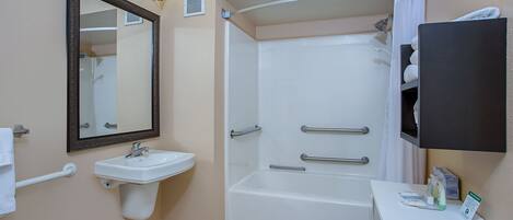 Une salle de bain équipée d’un lavabo, d’un miroir, d’une douche et d’un porte-serviettes.