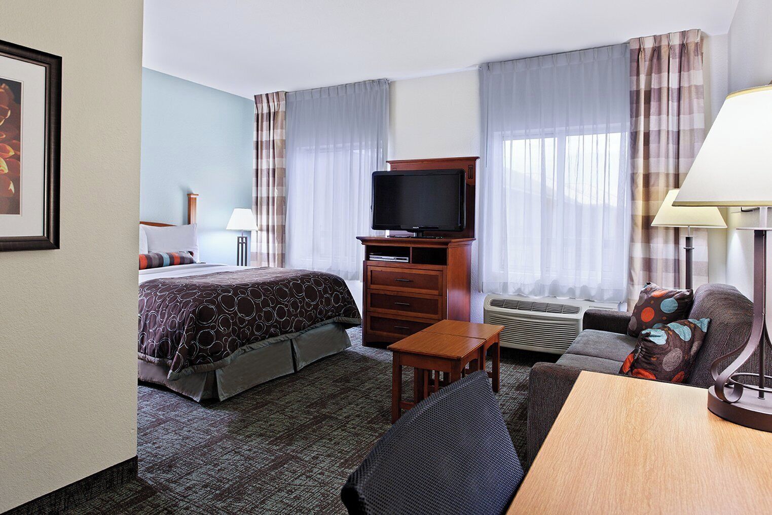 A hotel room with a bed, a TV, a desk, and a chair.
