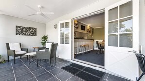Un patio abierto con zona de comedor, ventilador de techo y vista a la cocina.