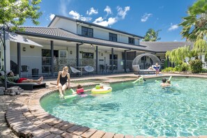 A swimming pool area with lounge chairs and a covered patio.
