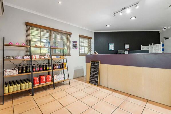 A clean, well-lit reception area with a counter, shelves stocked with products, and a chalkboard menu.