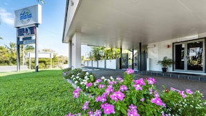 Un edificio moderno con un acceso cubierto, un cartel anunciando 'Alara Motor Inn' y una zona de recepción.