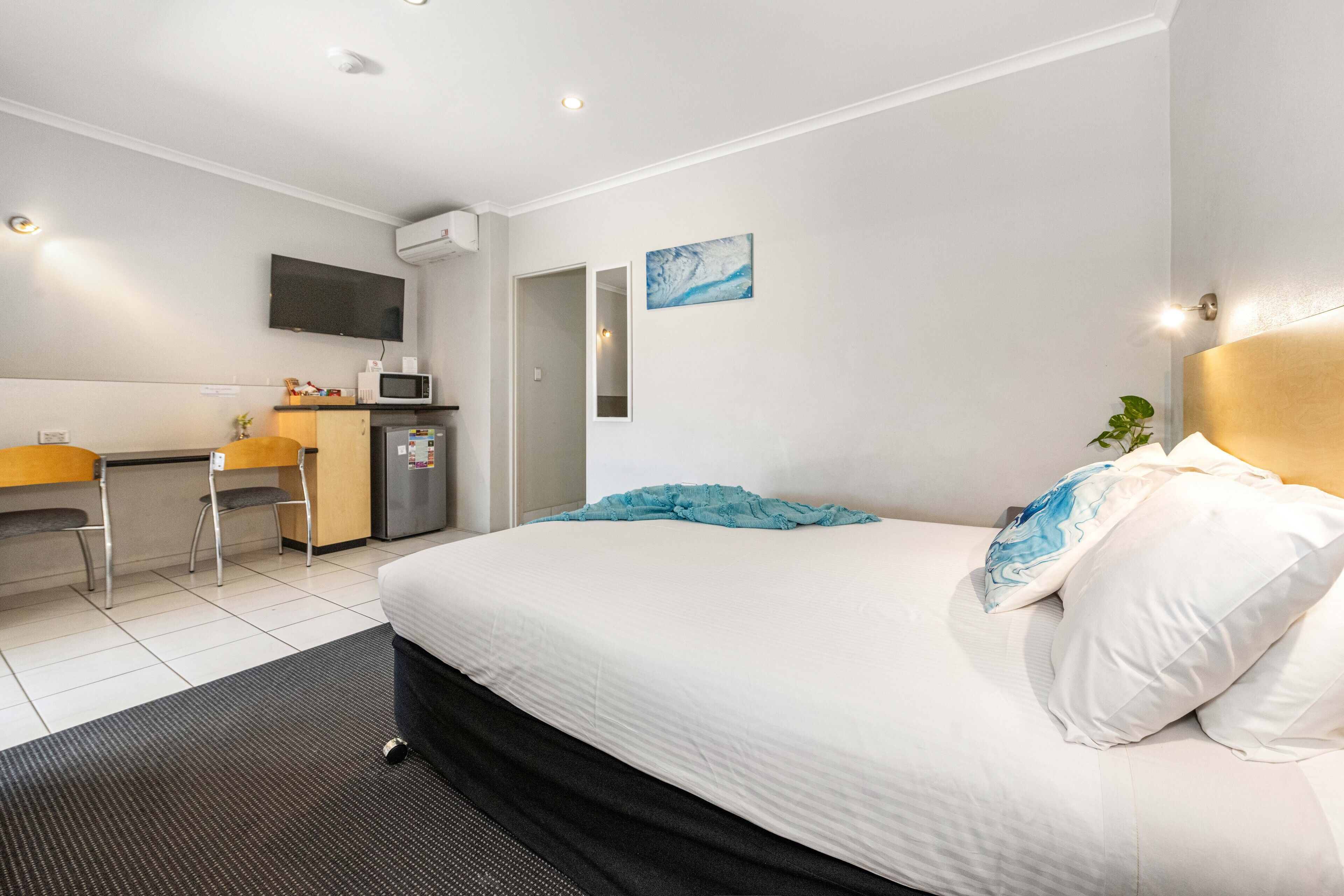 A hotel room with a bed, a desk, a microwave, and a TV.