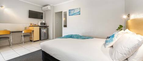Una habitación de hotel con cama, escritorio, microondas y televisión.