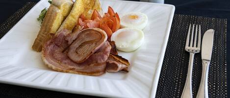 Un plato con tostadas, huevos, tocino y tomates sobre un plato blanco.
