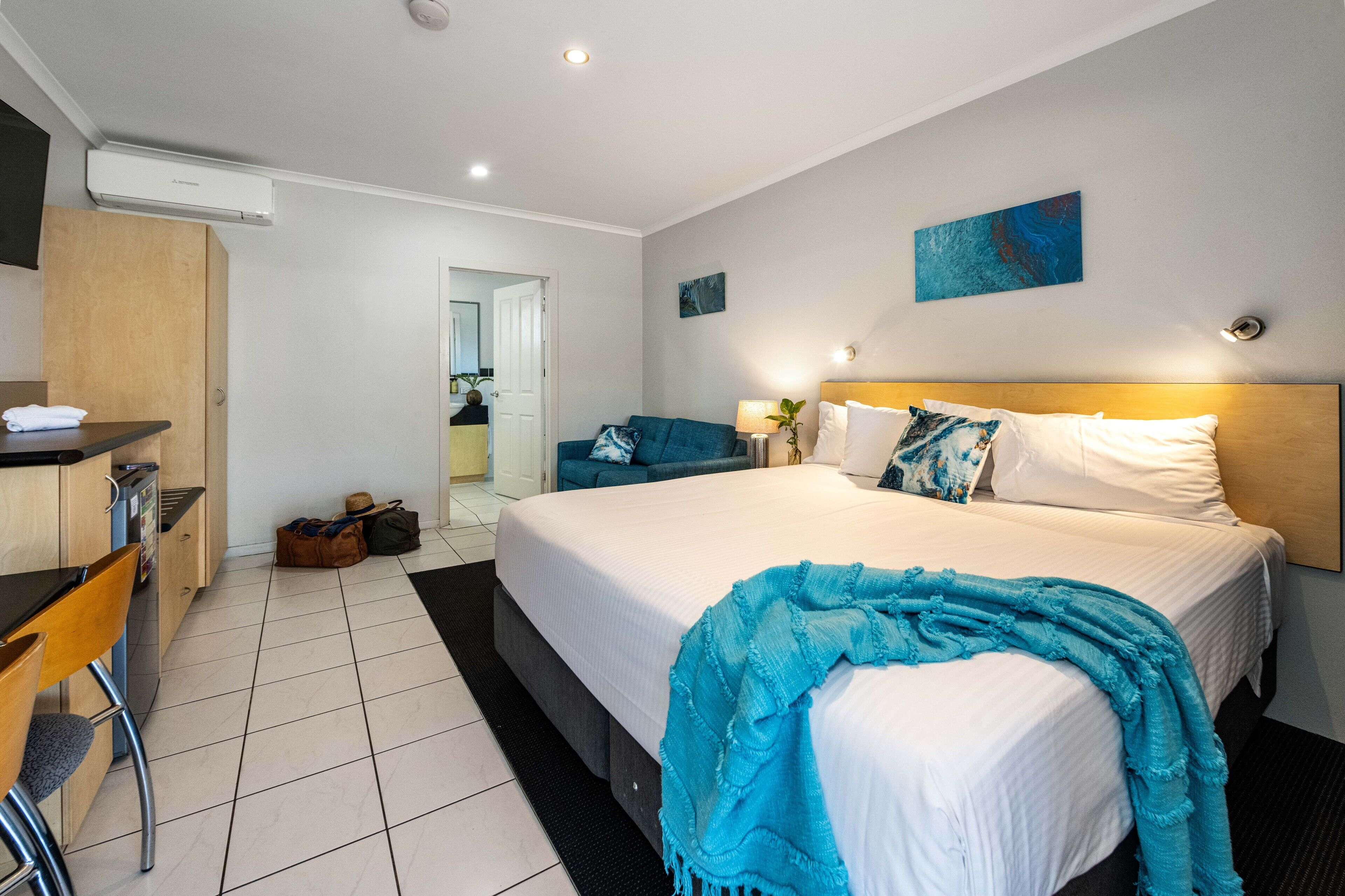 A hotel room with a large bed, a desk, a chair, and a wardrobe.
