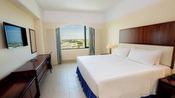A hotel room with a large bed, a desk, a TV, and a window with curtains.