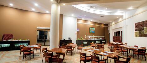 A spacious dining area with multiple tables and chairs, a counter with a menu, and a decorative wall.