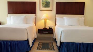 A hotel room with two beds, a nightstand with a lamp, and a framed picture on the wall.