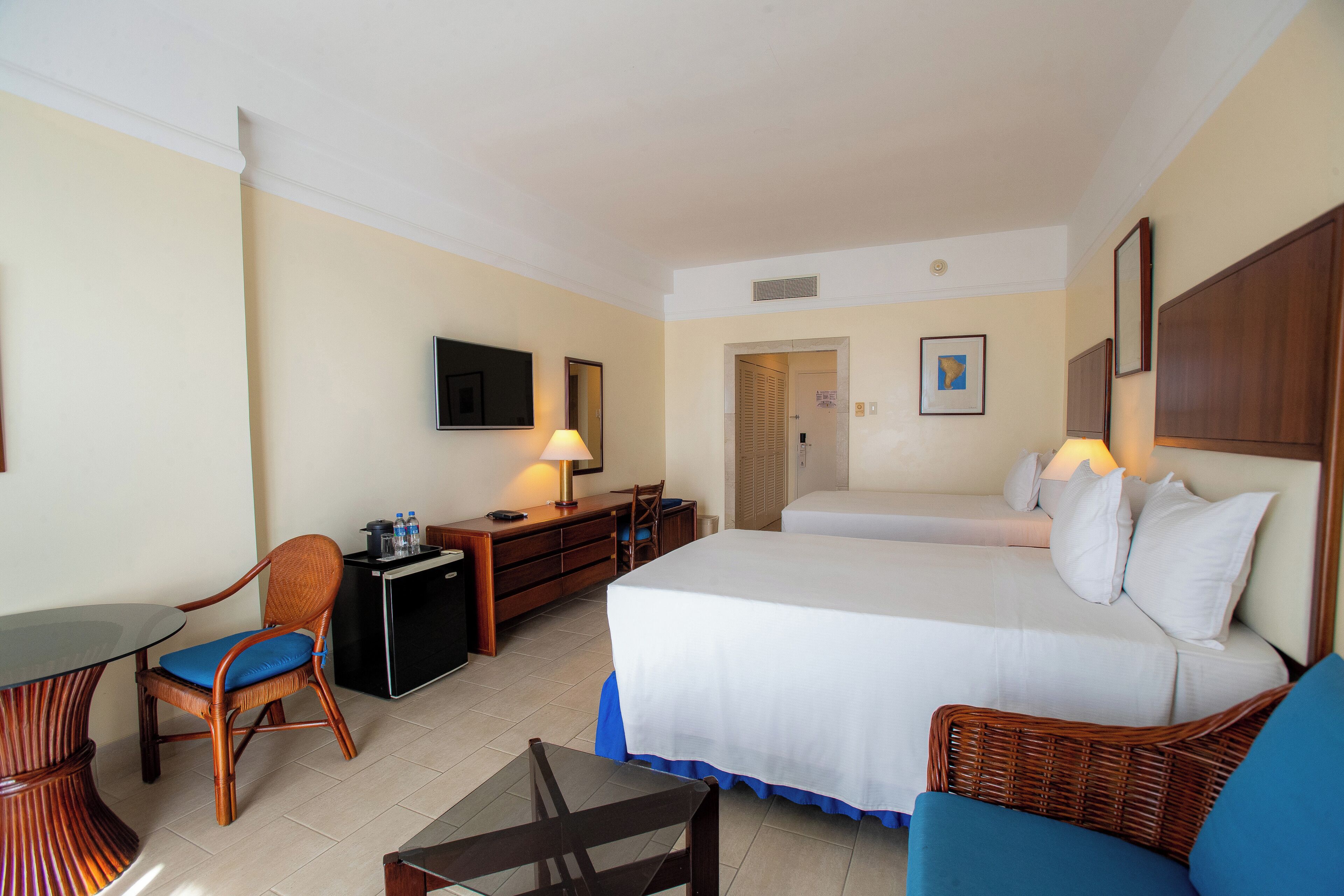 Una habitación de hotel con cama, escritorio, silla, televisor y lámpara.