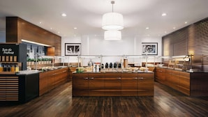 A modern kitchen with wooden cabinets, a central island, and pendant lighting. - NH Budapest City (Budapest)