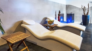 A spa area with two lounge chairs, a small wooden table, a bowl of fruit, and a decorative statue. - NH Budapest City (Budapest)