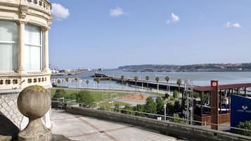 Vista costanera amb un edifici històric, un port esportiu i un cel serè.