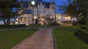 Un imposant bâtiment historique, doté d’une entrée remarquable, d’une pelouse bien entretenue et d’un chemin dégagé menant à l’entrée principale.