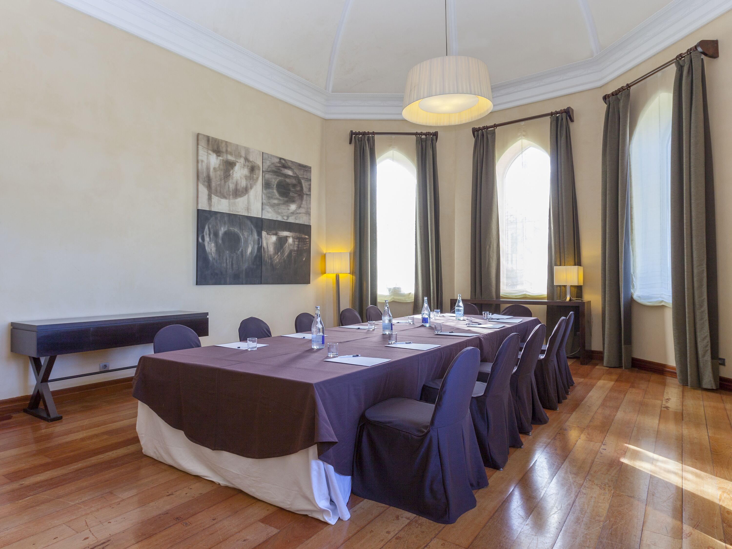 Un salón de conferencias con una larga mesa, sillas y un cuadro en la pared.
