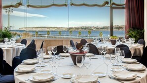 Un espace repas avec des tables dressées pour le repas, offrant une vue sur la côte.