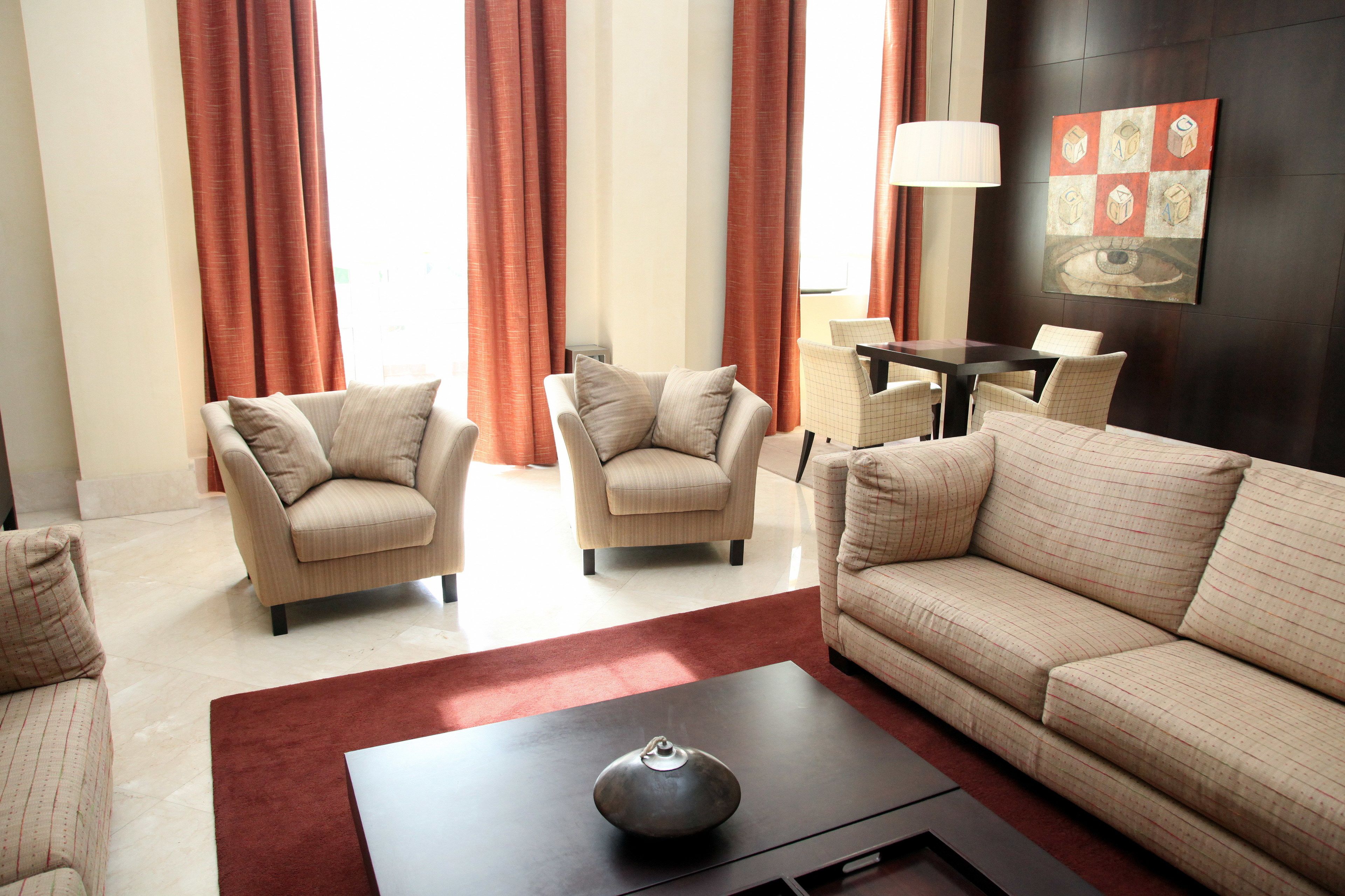 A modern living room with a sofa, two armchairs, a coffee table, and a dining table with chairs.