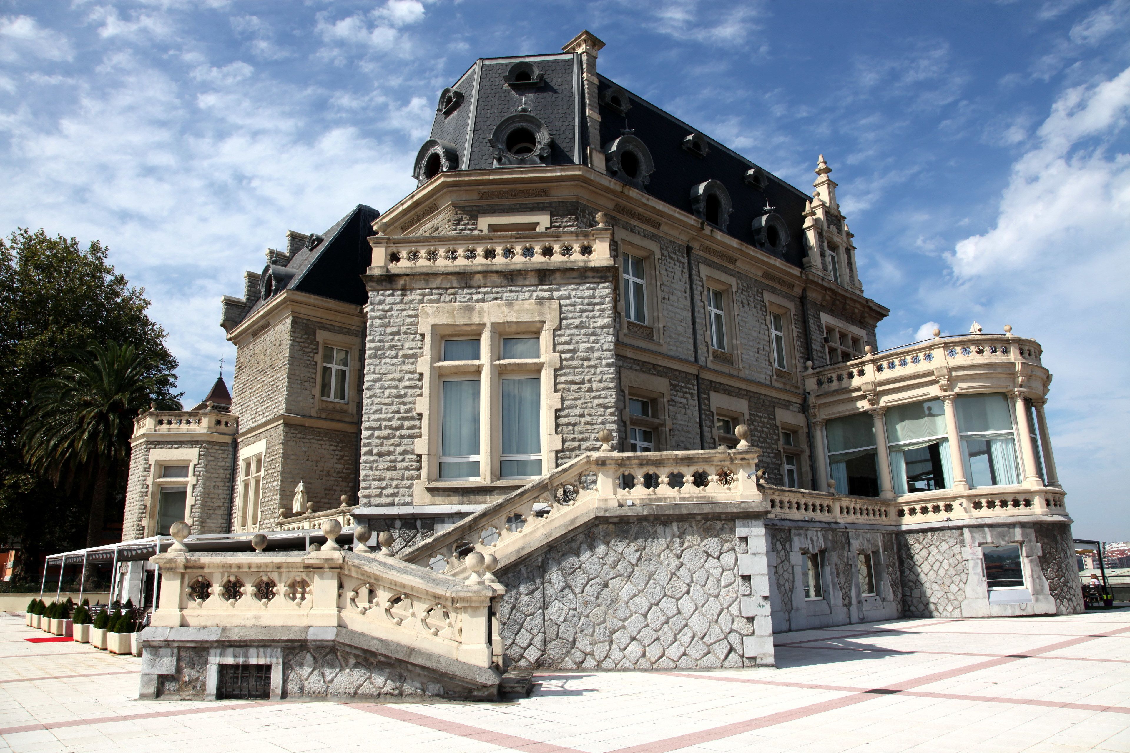 A historic building with a grand staircase, large windows, and ornate stonework.