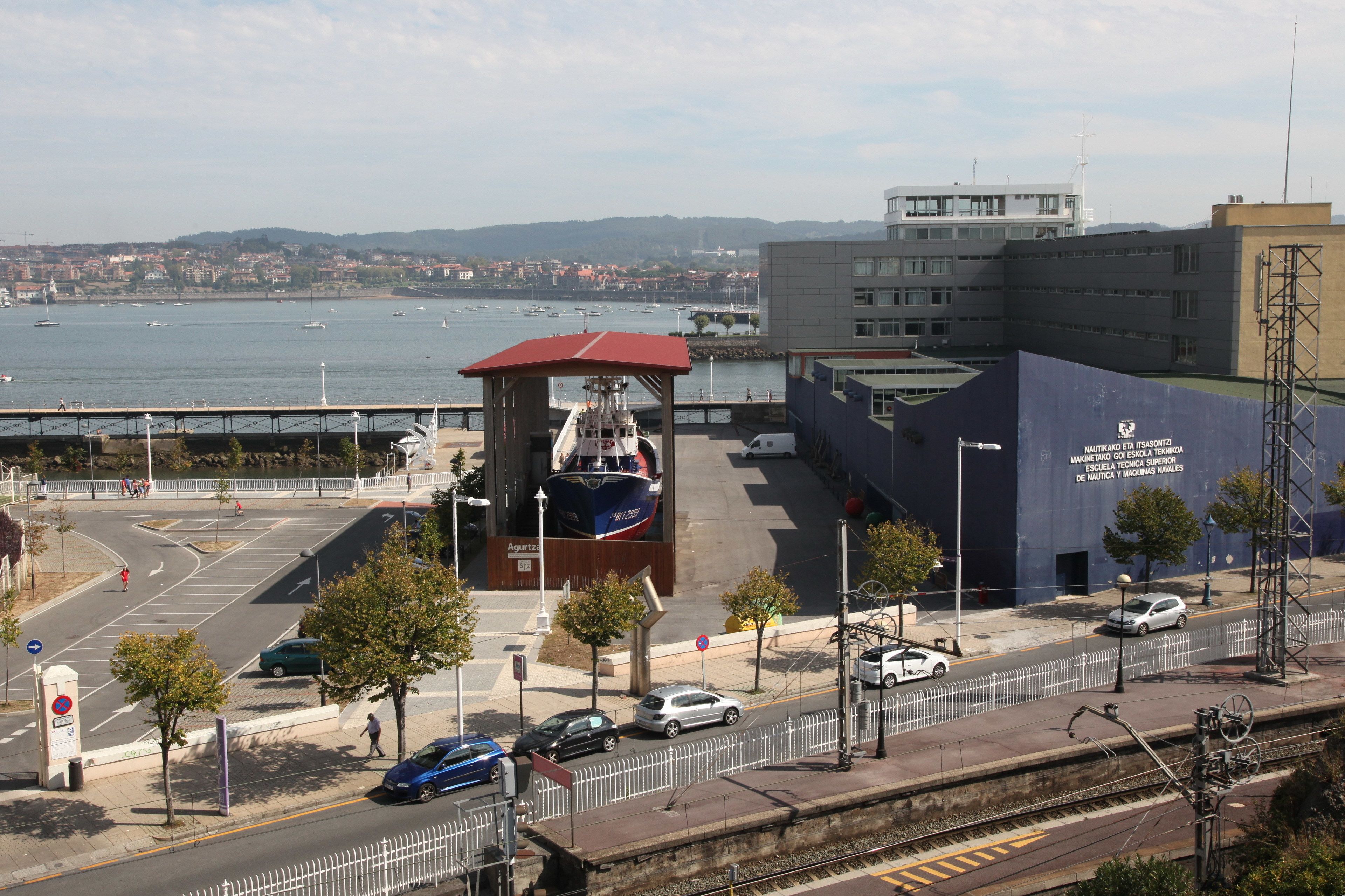 A coastal building with a red roof, a blue facade, and a sign indicating it is a technical school.