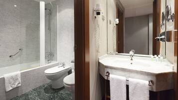 A modern bathroom with a glass-enclosed shower, a toilet, a sink with a mirror, and two towels hanging on the wall.