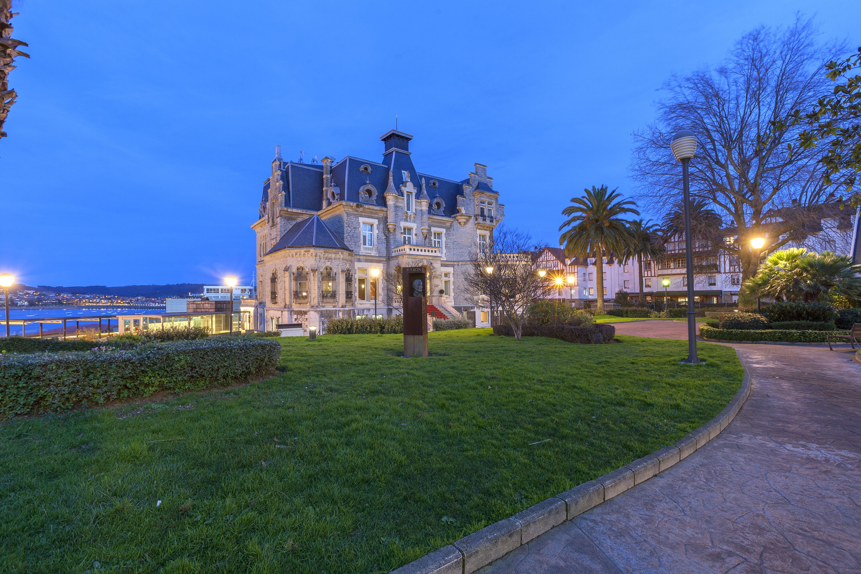 Um edifício histórico com um gramado bem cuidado e um caminho que leva à entrada.