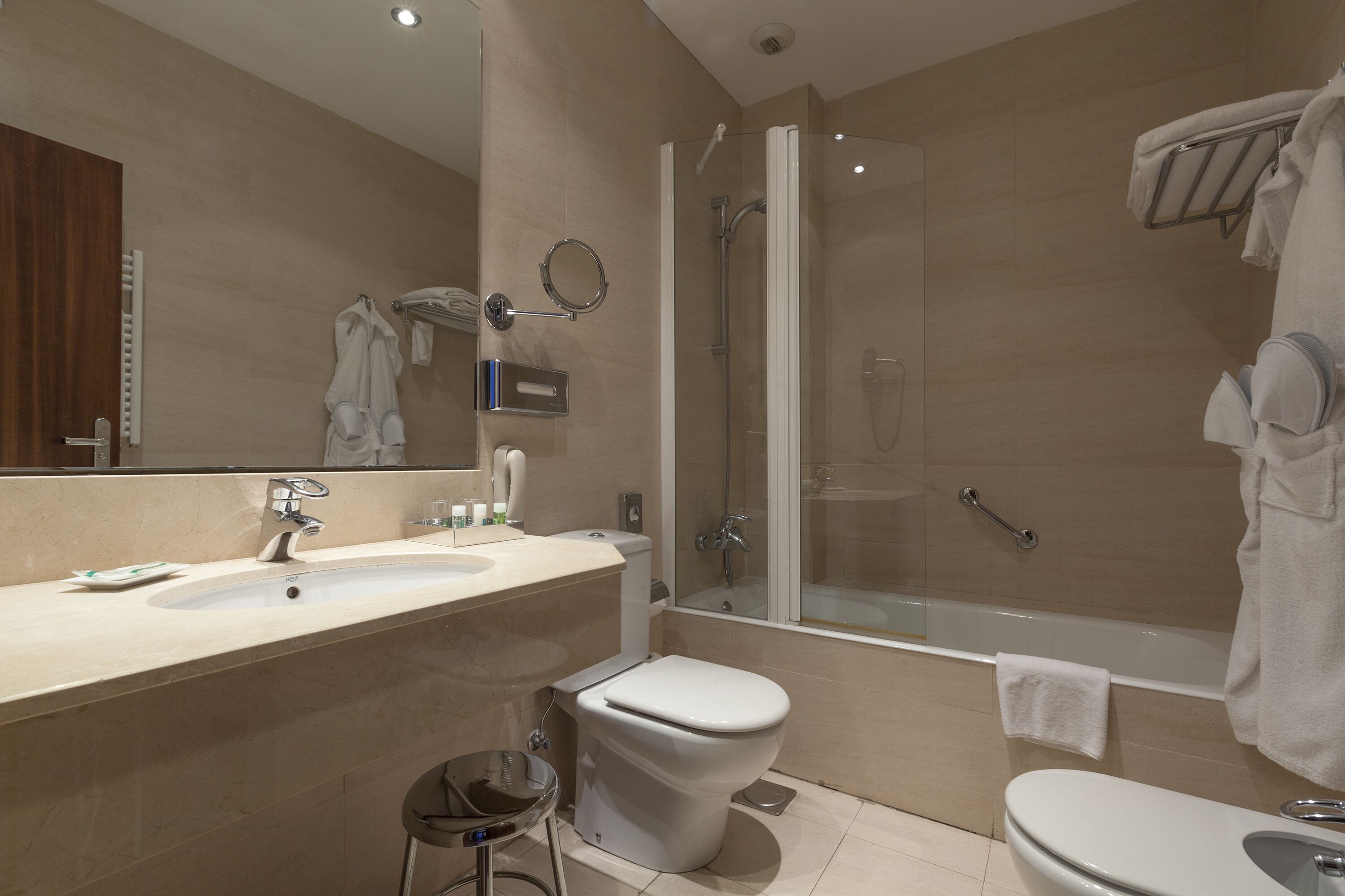 Un baño moderno con un espejo grande, un inodoro, un lavabo, una ducha y una bañera.