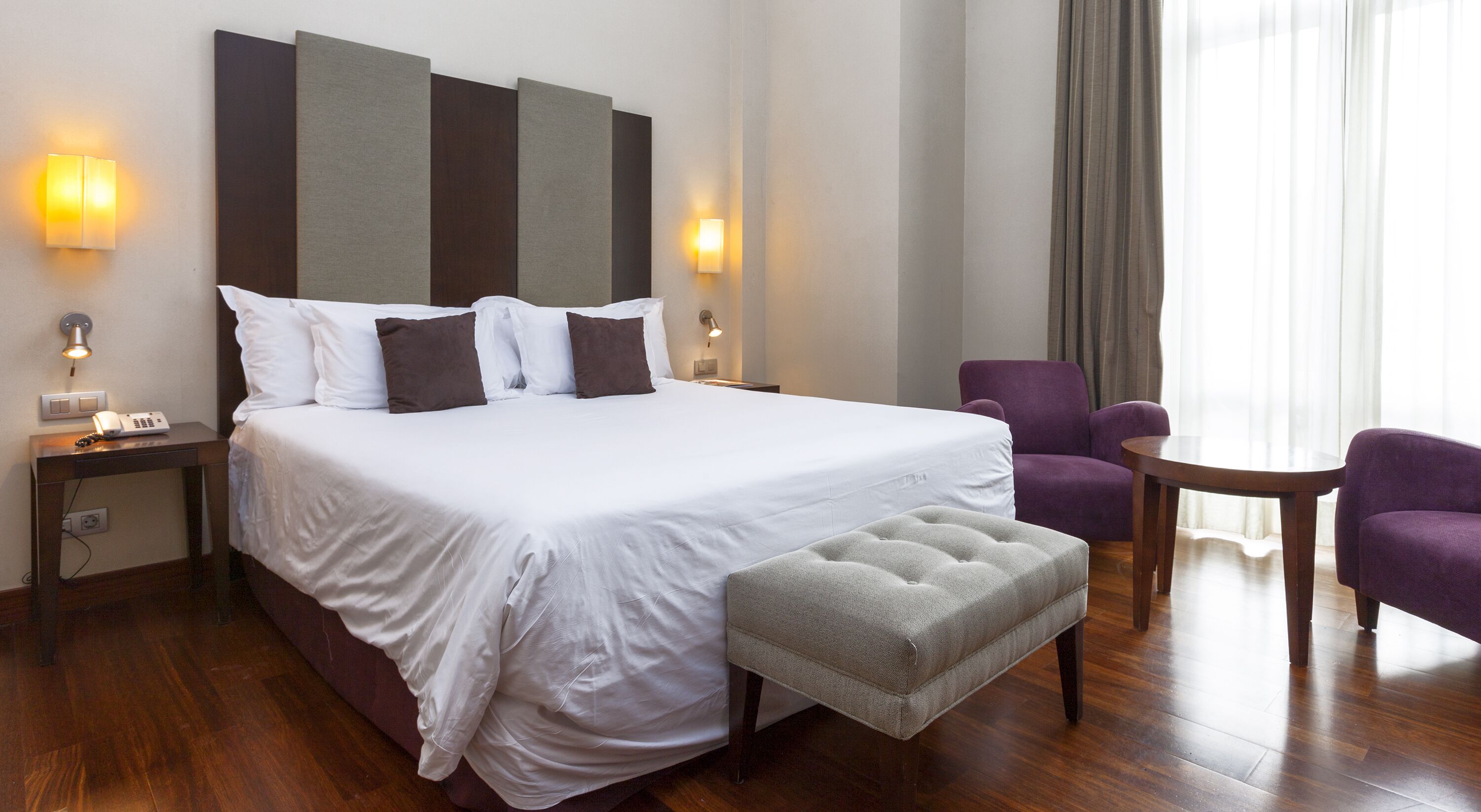 Una habitación de hotel con una cama grande, una mesita pequeña, una silla y un sofá.