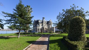 Un chemin de pierre mène à un grand bâtiment historique à la façade symétrique, doté de plusieurs tours.
