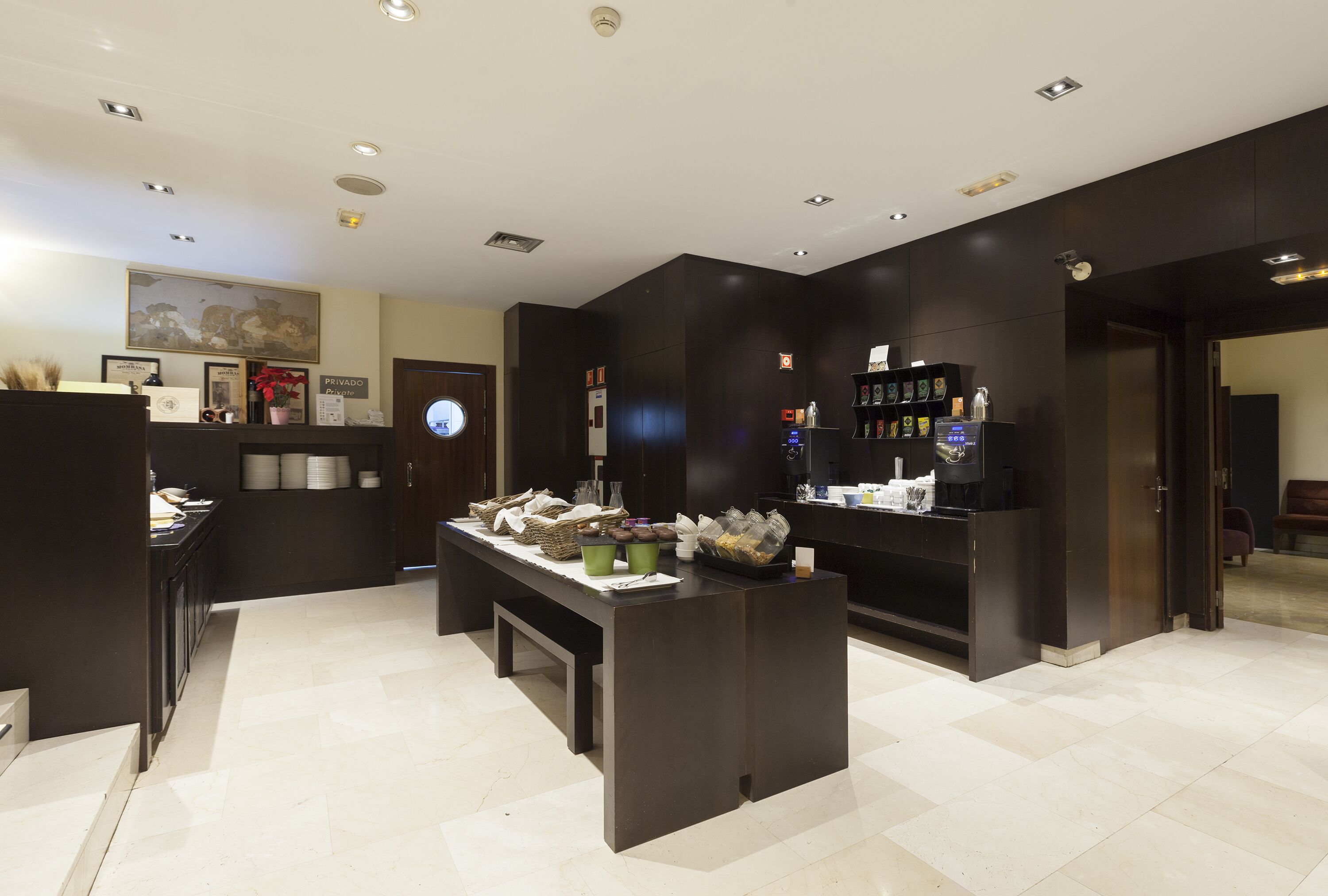 Un moderno vestíbulo de hotel con una recepción, una máquina de café y una estantería.
