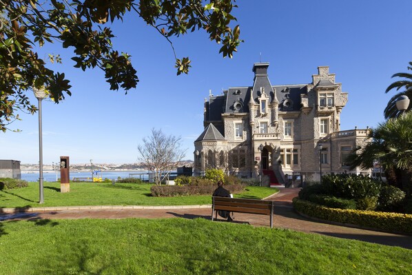 A historic building with a large lawn and a bench.
