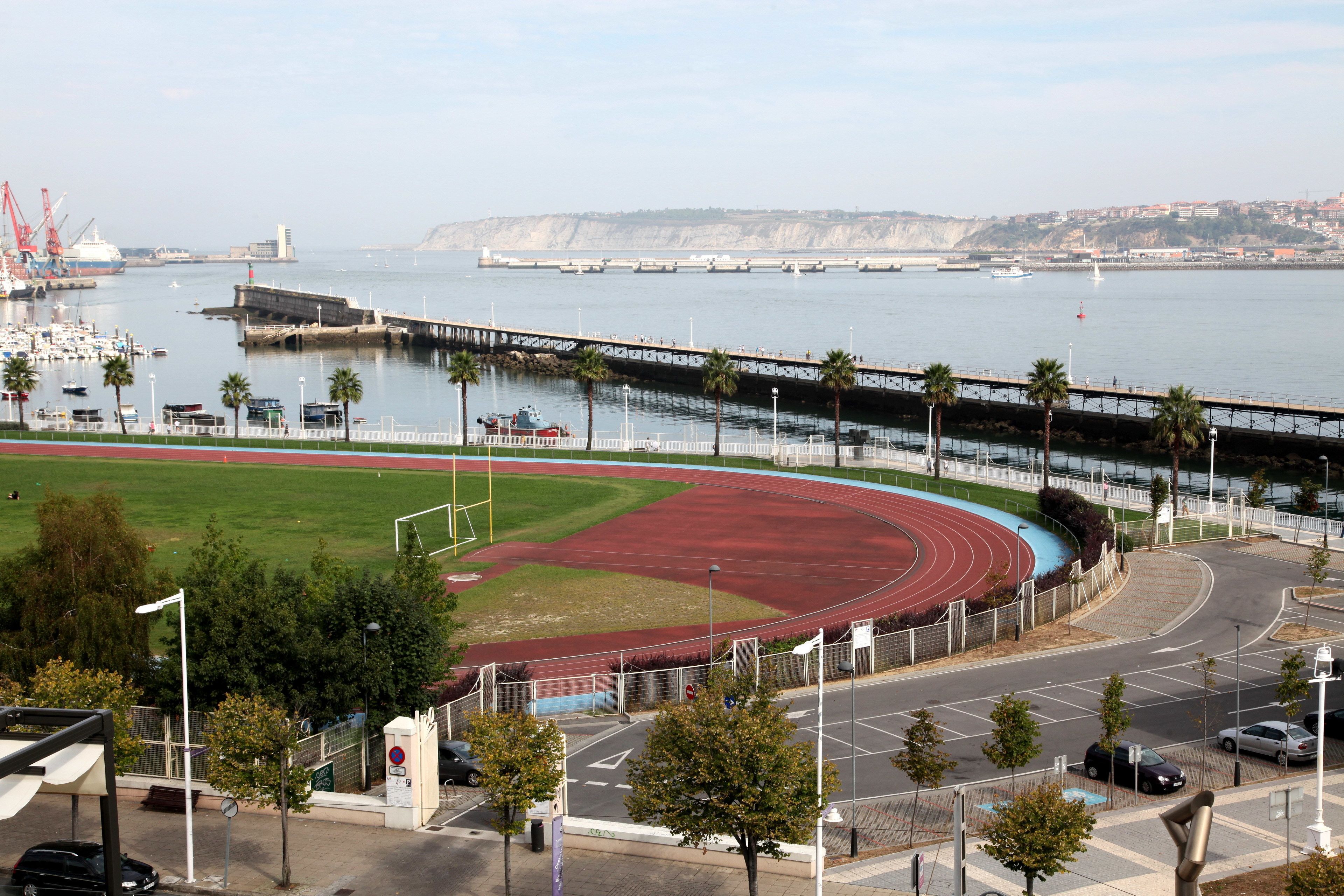 Un complexe sportif situé sur la côte, comprenant une piste d’athlétisme, un stade et un port de plaisance.