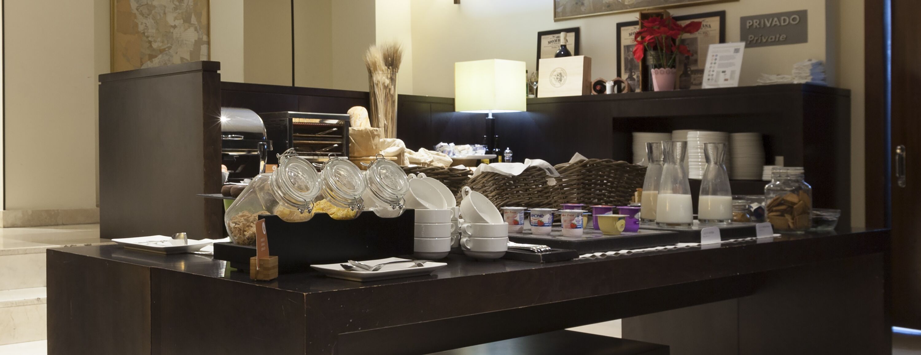 A hotel reception area with a coffee station, a private label sign, and a counter with various food items and containers.