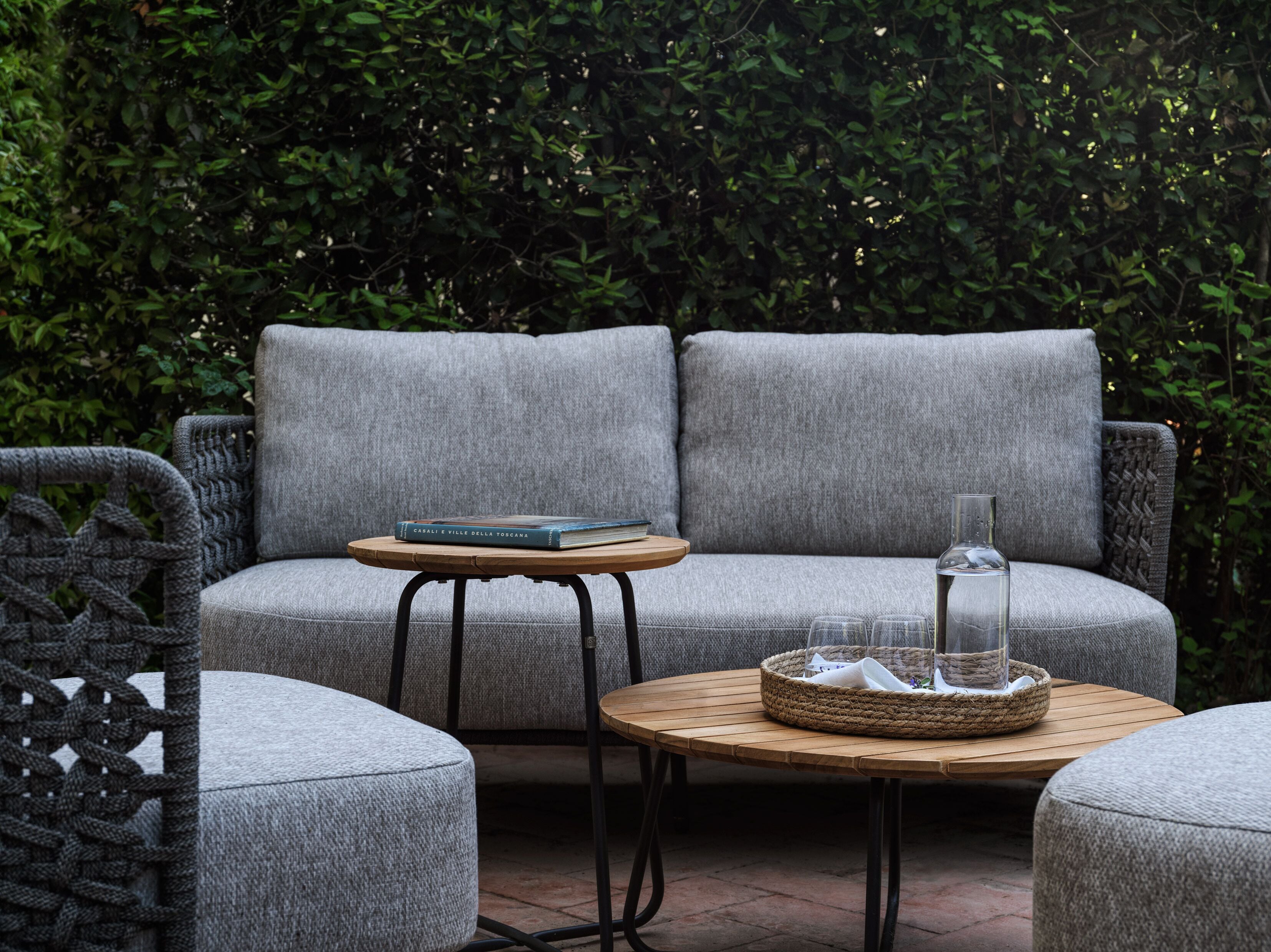 A grey sofa set with a small round table and a wicker basket.