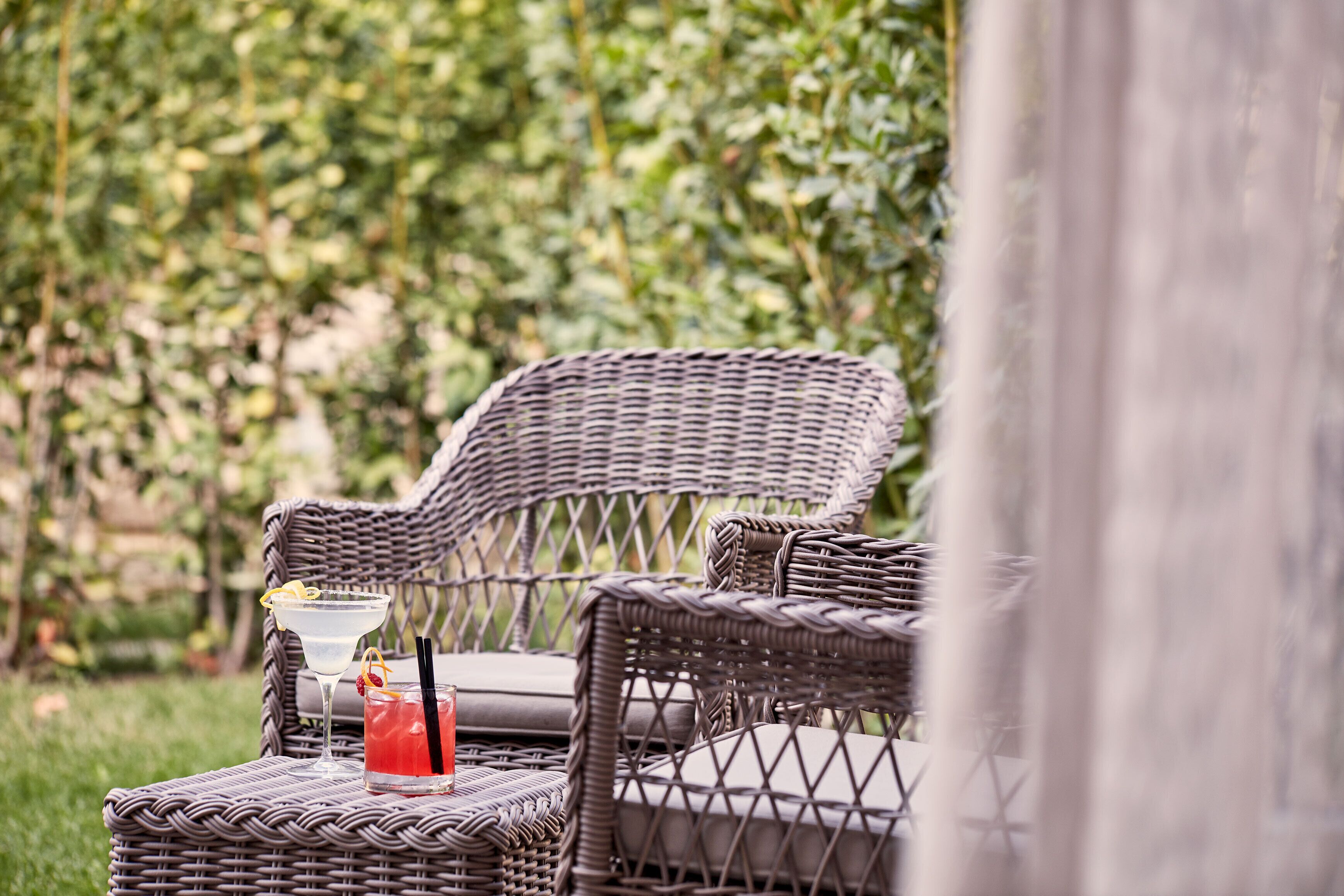 Wicker chairs with cushions and a table with a drink.
