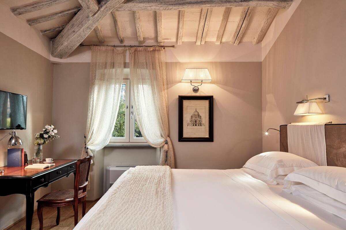 A bedroom with a bed, a desk, a chair, a lamp, and a framed picture on the wall.