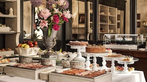 A buffet with various food items, a vase of flowers, and a mirror reflecting the room.