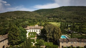A large estate with a swimming pool, surrounded by lush greenery and hills.