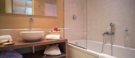 Un baño moderno con un lavamanos grande, una bañera y una ducha con cerramiento de vidrio.