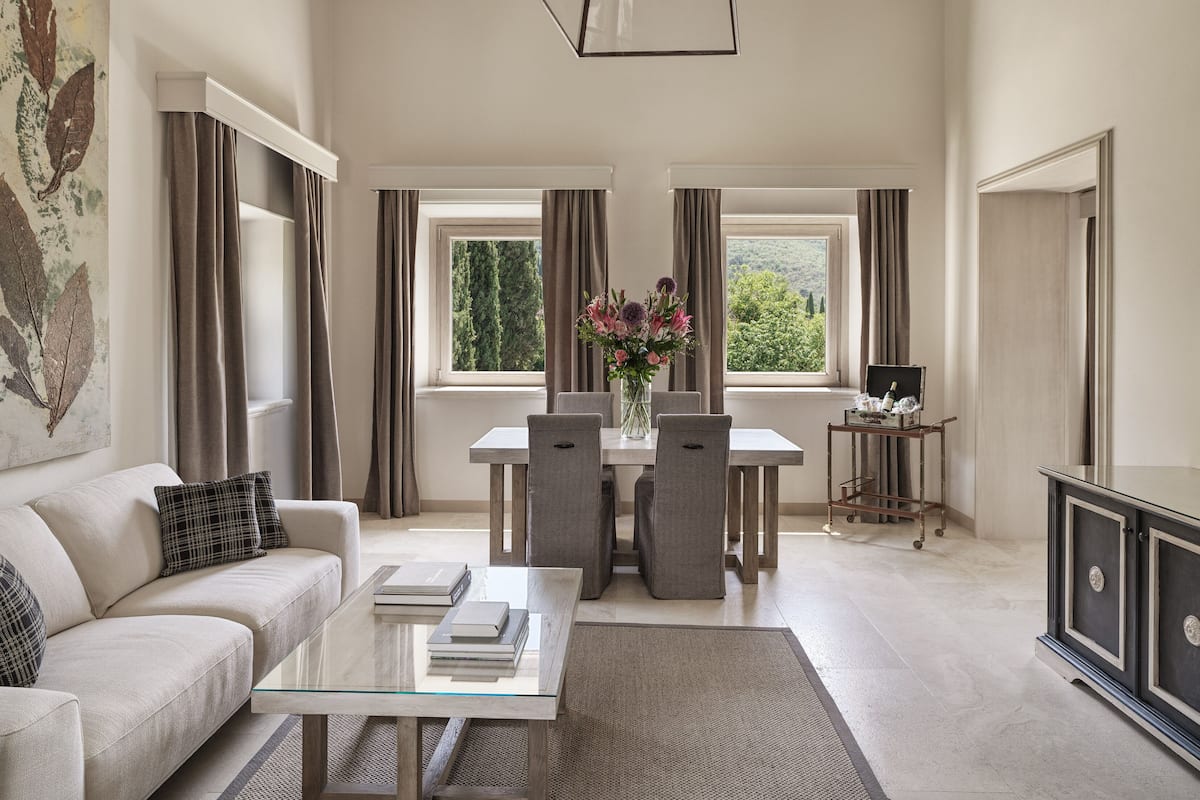 A spacious living room with a glass coffee table, a sofa, and a dining area with a table and chairs.