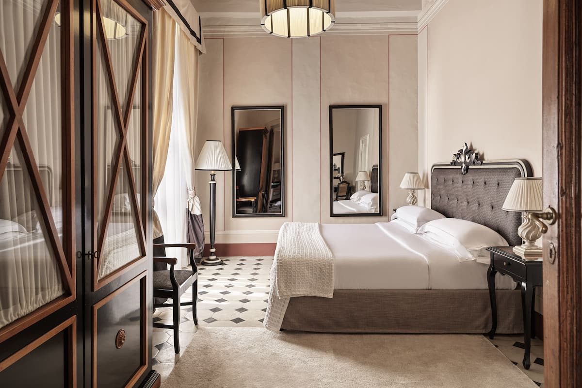 A hotel room with a large bed, a wardrobe, a desk, and a mirror.