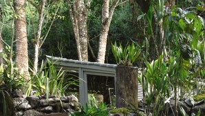 A waterfall cascading over a stone structure surrounded by lush greenery.