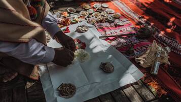 A person arranging items on a table with various objects and a patterned cloth.